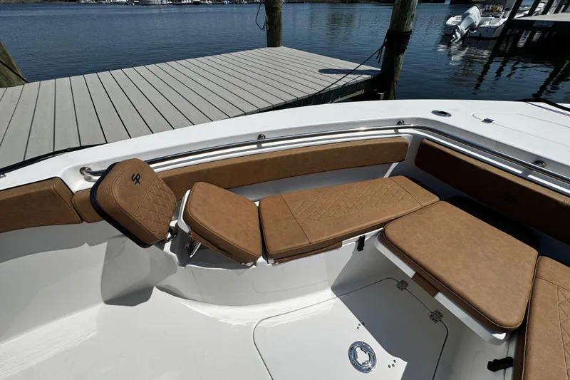 Slide: The Image of 2024 Sea Pro 239 Deep V CC boat interior with tan cushioned seating by the dock. - 99