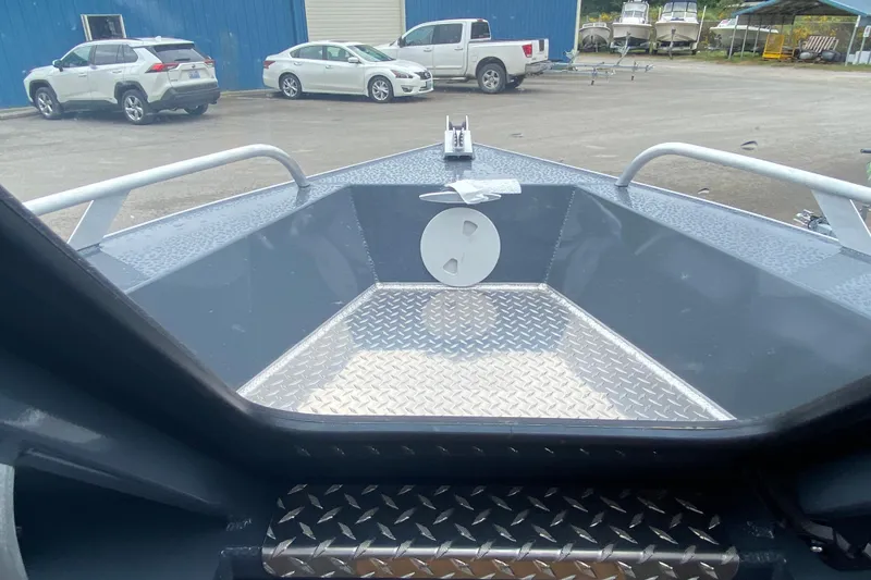 Slide: The Image of 2026 Hewescraft 160 Sportsman boat interior with diamond plate flooring, parked cars in background. - 10