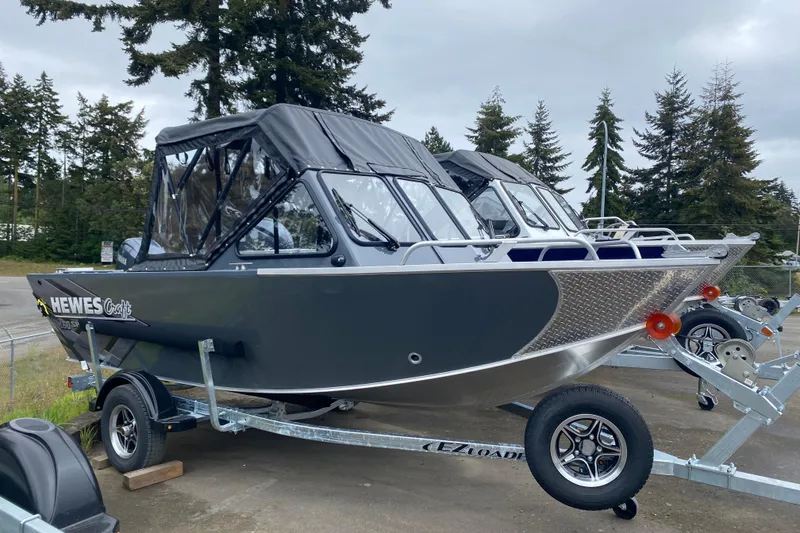 Slide: The Image of 2026 Hewescraft 160 Sportsman boat on trailer, parked outdoors with trees in background. - 2
