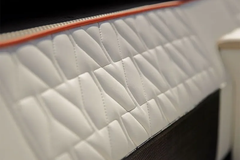 Slide: The Image of Close-up of white quilted upholstery with orange trim on a boat. - 23