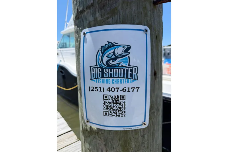 Slide: The Image of Sign for Big Shooter Fishing Charters with contact number and QR code on a dock. - 13