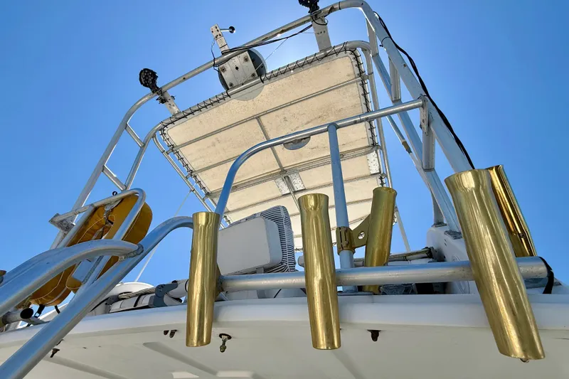Slide: The Image of Baja Cruiser King Cat 340 boat tower with gold rod holders, under clear blue sky. - 65