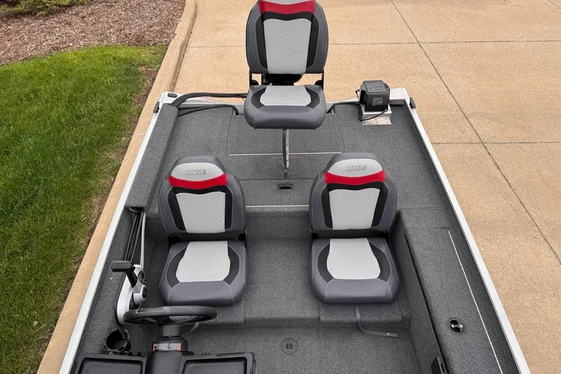 Slide: The Image of 2019 Lowe Skorpion 16 boat interior with three gray and red seats on a carpeted deck. - 7