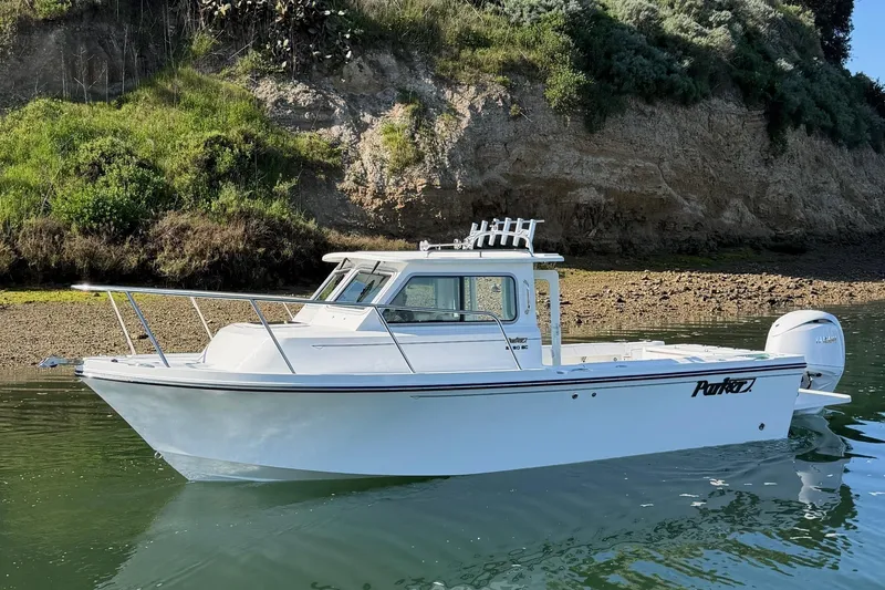 The Image of Parker 227 Explorer 2026 boat on calm water near rocky shoreline. - 1