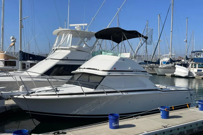 The Image of 1987 Bertram 28 Flybridge boat docked at marina with clear blue sky. - 0