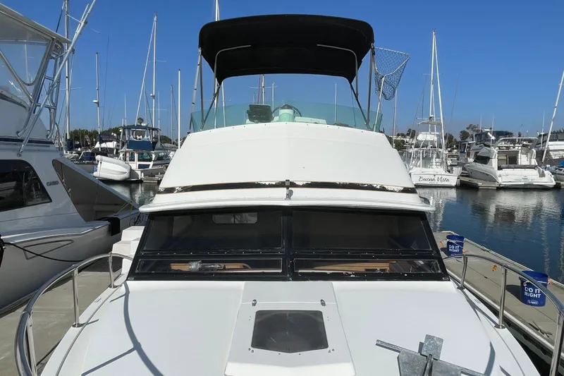 Slide: The Image of 1987 Bertram 28 Flybridge boat docked in a marina, surrounded by other vessels. - 10