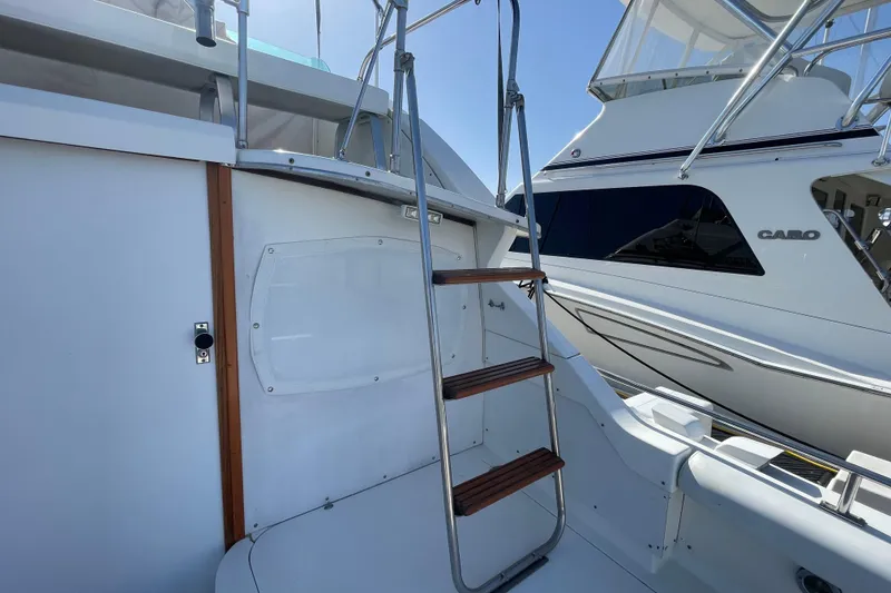 Slide: The Image of 1987 Bertram 28 Sport Fisherman boat with ladder and adjacent vessel in marina. - 11