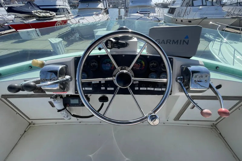 Slide: The Image of 1987 Bertram 28 Flybridge helm with Garmin navigation, docked among other boats. - 14