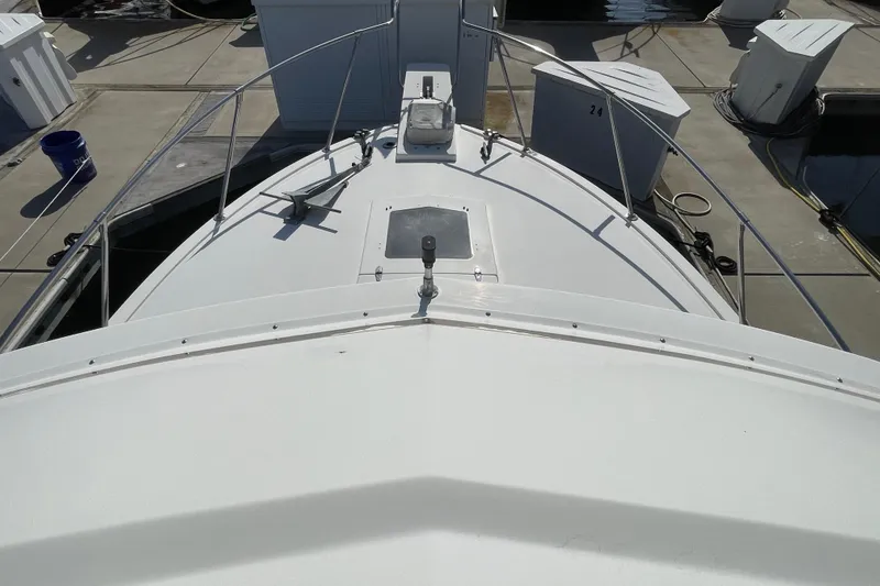 Slide: The Image of 1987 Bertram 28 Flybridge boat docked, showcasing its bow and deck details. - 16