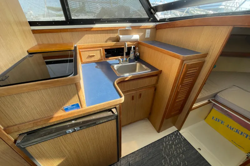 Slide: The Image of Interior of 1987 Bertram 28 Flybridge with compact kitchen and sink area. - 24