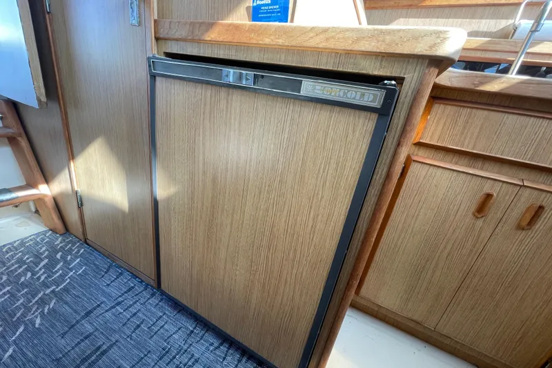 Slide: The Image of 1987 Bertram 28 Flybridge interior with wood paneling and Norcold refrigerator. - 25