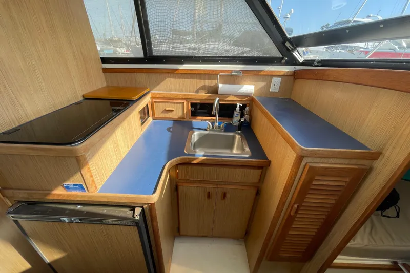 Slide: The Image of 1987 Bertram 28 Flybridge boat kitchen with sink, countertop, and wooden cabinetry. - 26
