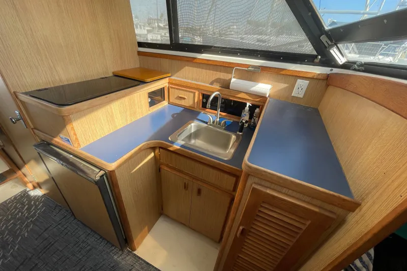 Slide: The Image of 1987 Bertram 28 Flybridge boat kitchen with sink, stove, and wooden cabinetry. - 28