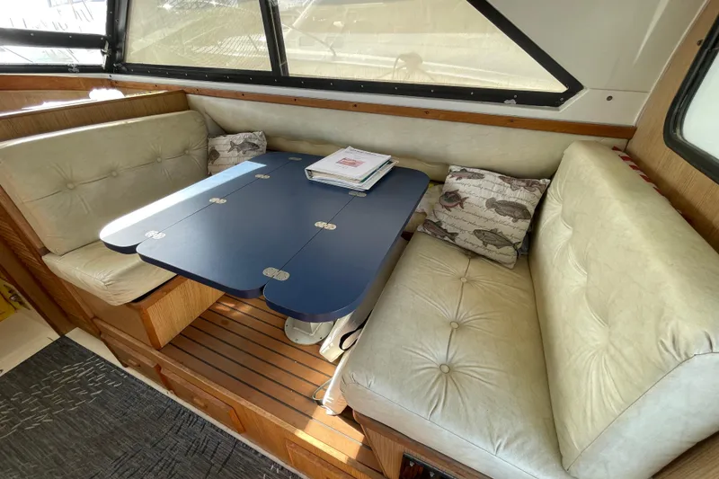 Slide: The Image of Interior of a 1987 Bertram 28 Flybridge with cushioned seating and a blue table. - 30