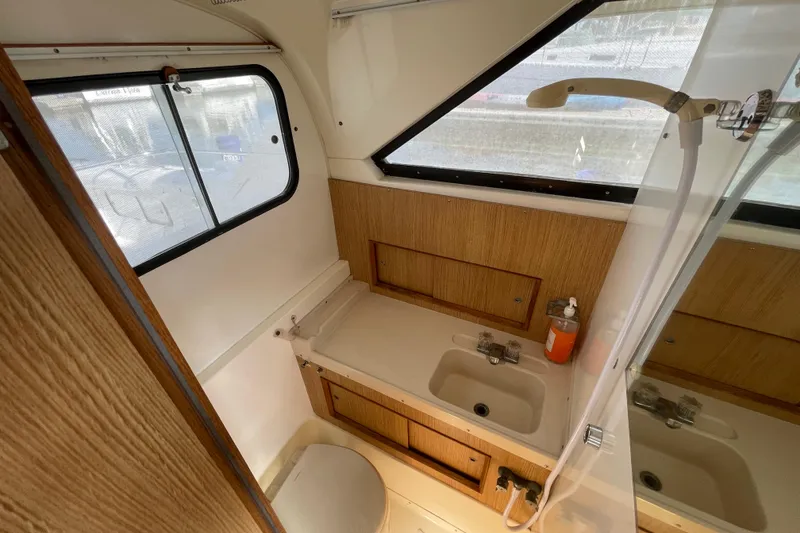 Slide: The Image of 1987 Bertram 28 Flybridge bathroom with sink, shower, and wooden cabinetry. - 34