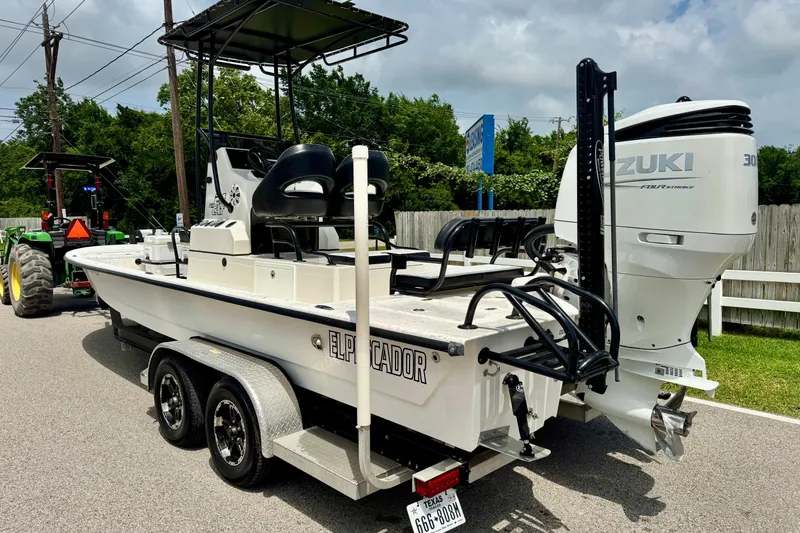 Slide: The Image of 2022 El Pescador 24 CAT boat with Suzuki engine on trailer, parked outdoors. - 2
