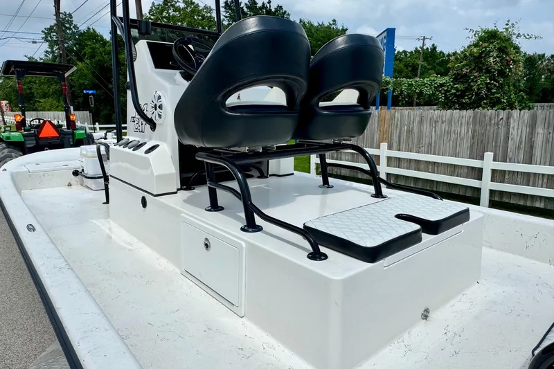 Slide: The Image of 2022 El Pescador 24 CAT boat interior with dual seats and console, parked outdoors. - 8