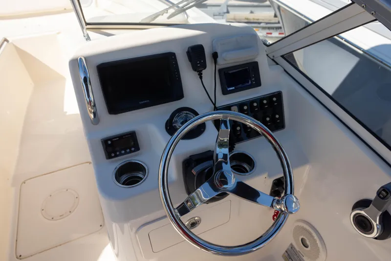Slide: The Image of 2018 Grady-White Freedom 215 boat dashboard with steering wheel and navigation controls. - 18