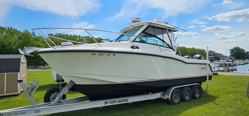 The Image of 2016 Boston Whaler 285 Conquest boat on trailer, parked on grass under blue sky. - 0