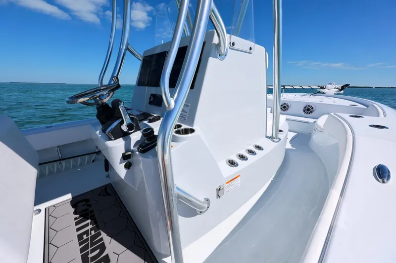 Slide: The Image of 2026 Contender 29 Bay boat console with steering wheel, on open water under blue sky. - 16