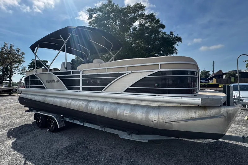 The Image of 2015 AquaPatio 250 WB pontoon boat on trailer under sunny sky. - 0