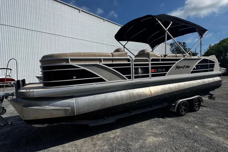 Slide: The Image of 2015 AquaPatio 250 WB pontoon boat with canopy on trailer, parked outdoors. - 10