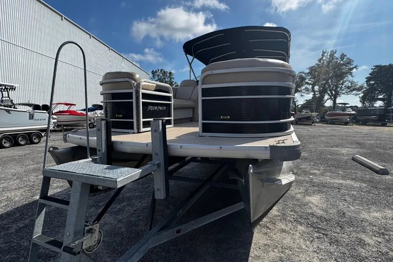 Slide: The Image of 2015 AquaPatio 250 WB pontoon boat on trailer, parked outdoors under a sunny sky. - 9
