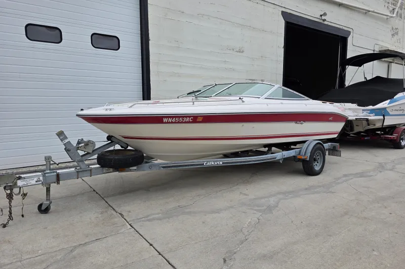 The Image of 1993 Searay 200 boat on trailer, parked outside a garage. - 0