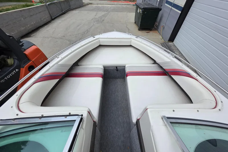 Slide: The Image of 1993 Searay 200 boat interior with white and red seating, docked near a warehouse. - 12