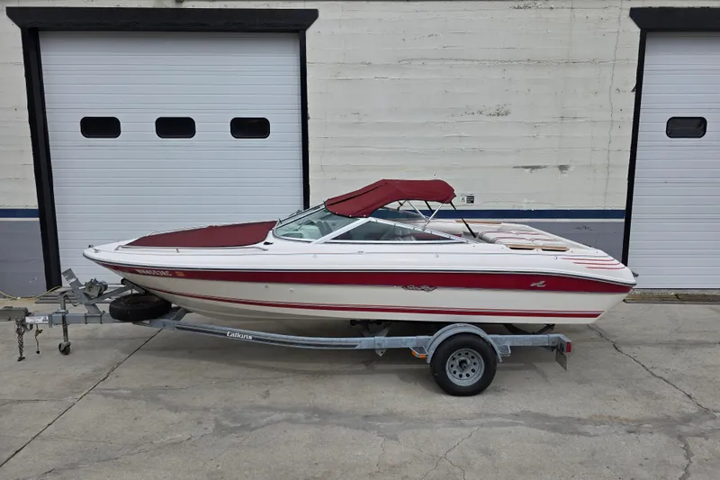 Slide: The Image of 1993 Searay 200 boat on trailer, parked in front of garage doors. - 2