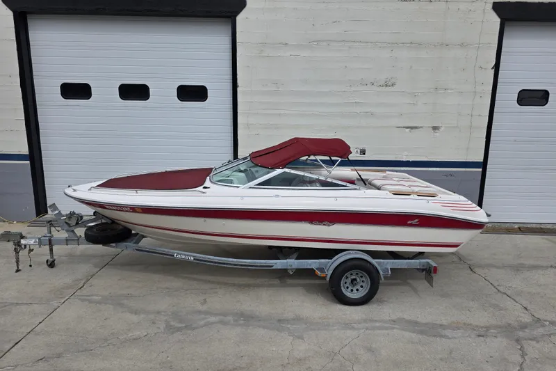 Slide: The Image of 1993 Searay 200 boat with red canopy on trailer, parked outside garage doors. - 3