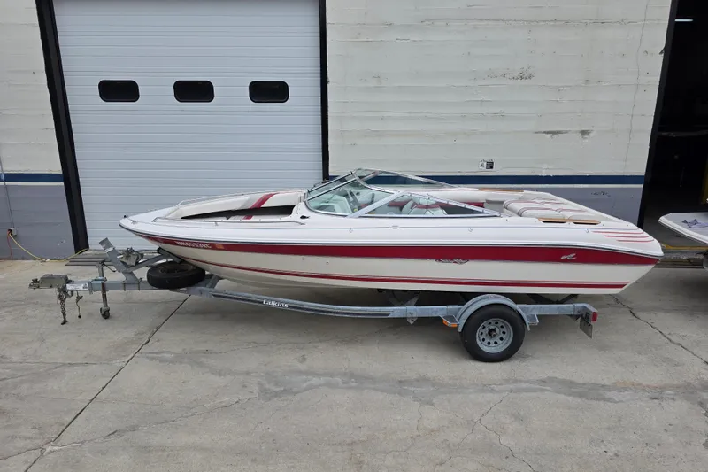 Slide: The Image of 1993 Searay 200 boat on trailer, parked outside a garage door. - 5