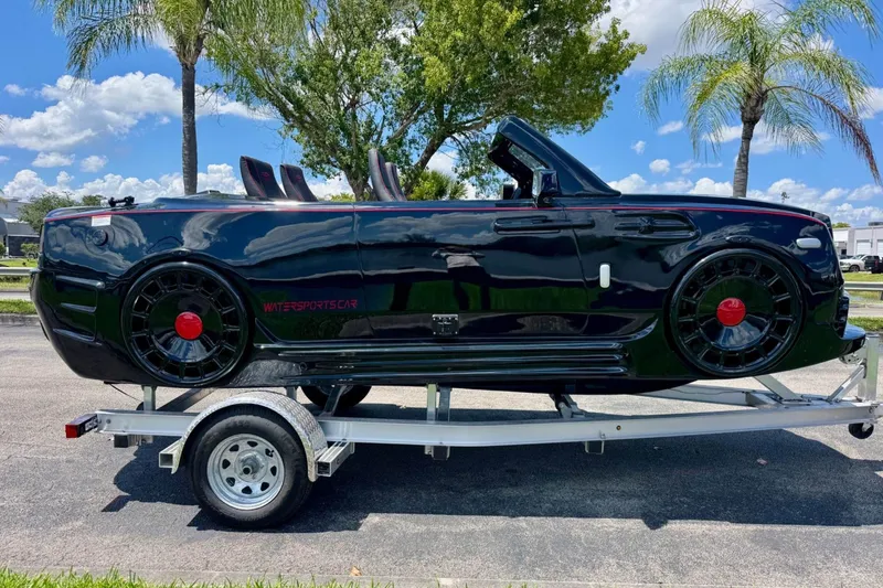 Slide: The Image of 2025 Watersports Car Series R on trailer, sleek black design, palm trees in background. - 6