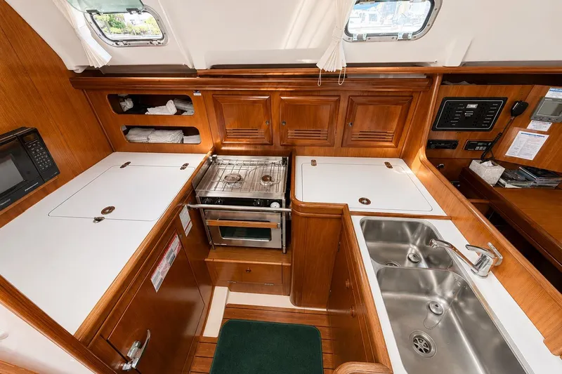 Slide: The Image of 2001 Beneteau 361 yacht kitchen with wood cabinetry, dual sink, stove, and microwave. - 10