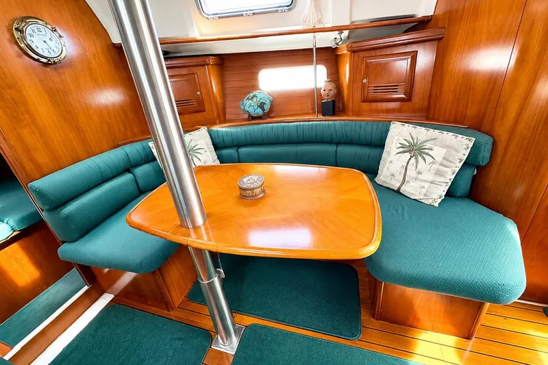 Slide: The Image of Interior of 2001 Beneteau 361 sailboat with wooden table and green seating. - 13