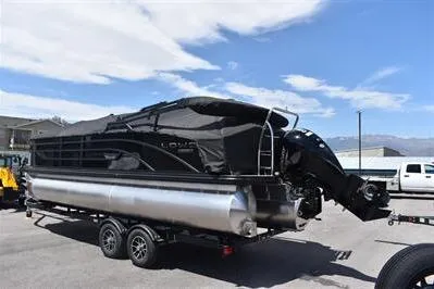 Slide: The Image of 2026 Lowe SF 232 Sport Fish pontoon boat on trailer, parked outdoors under a cloudy sky. - 2