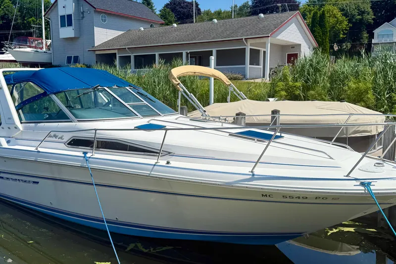 The Image of 1992 Sea Ray 290 Sundancer boat docked near a house with lush greenery. - 0