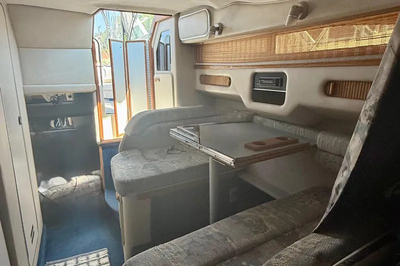 Slide: The Image of Interior of a 1992 Sea Ray 290 Sundancer boat, featuring cozy seating and a table. - 12