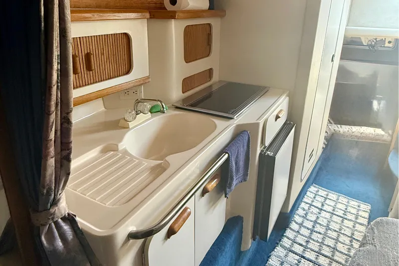 Slide: The Image of 1992 Sea Ray 290 Sundancer interior kitchen with sink, stove, and storage cabinets. - 13