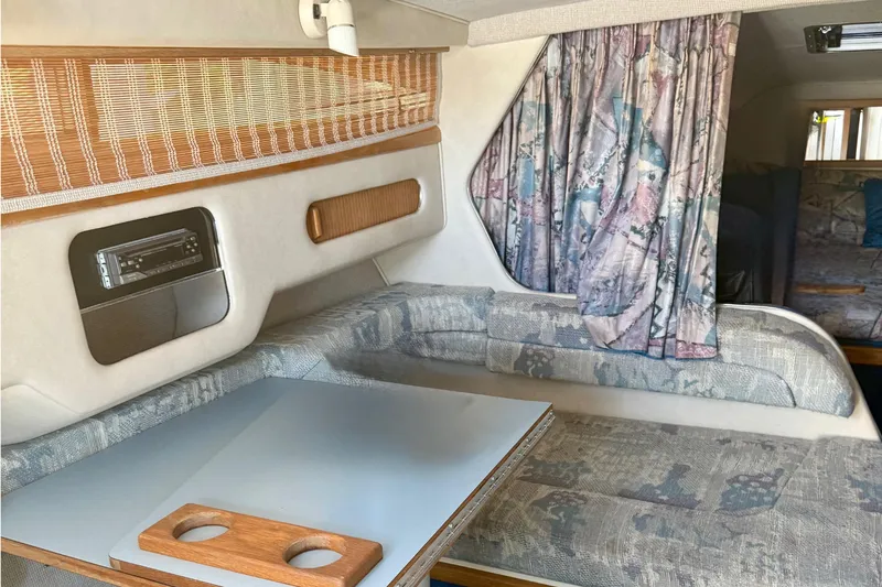 Slide: The Image of Interior of 1992 Sea Ray 290 Sundancer boat with seating, table, and patterned curtains. - 14