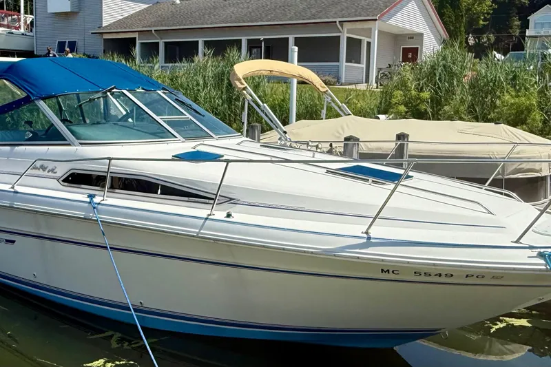 Slide: The Image of 1992 Sea Ray 290 Sundancer boat docked near a house with greenery. - 3