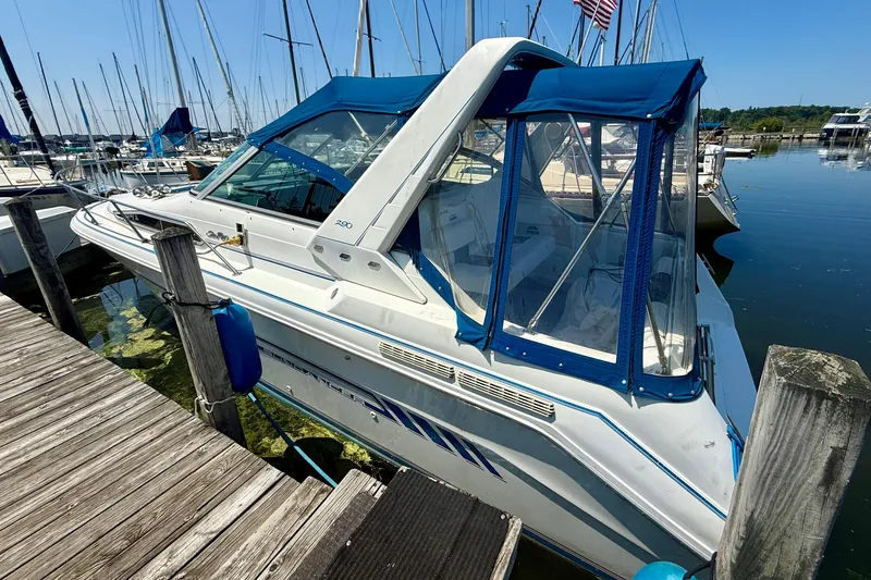 Slide: The Image of 1992 Sea Ray 290 Sundancer docked at a marina, featuring blue canopy and sleek design. - 4