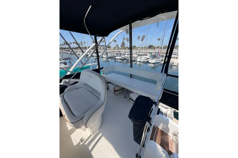 Slide: The Image of 2007 Silverton 33 Convertible yacht interior with marina view, featuring seating and helm area. - 8