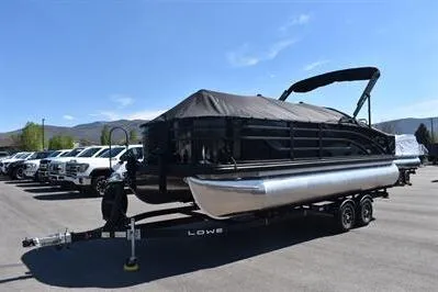 Slide: The Image of 2026 Lowe SF 214 Sport Fish pontoon boat on trailer, parked outdoors under clear sky. - 1