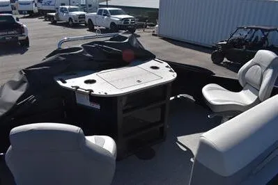 Slide: The Image of 2026 Lowe SF 214 Sport Fish boat interior with seating and storage, parked outdoors. - 27
