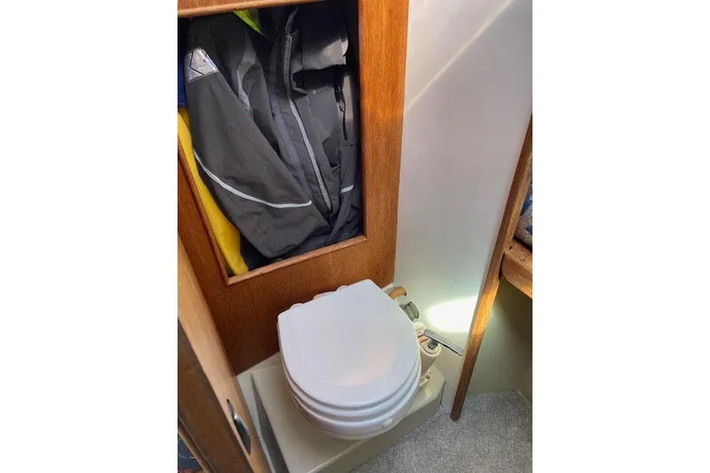 Slide: The Image of 1977 C&C 29 sailboat interior with compact marine toilet and storage area. - 10