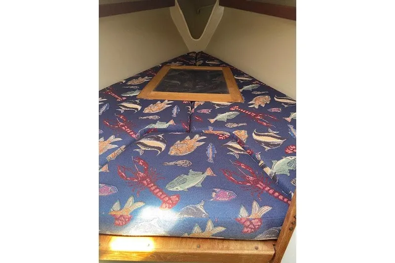Slide: The Image of 1977 C&C 29 sailboat cabin with fish-patterned bedding and wooden accents. - 5