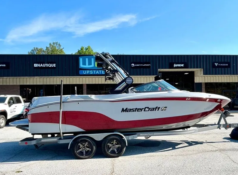 The Image of 2022 MasterCraft XT23 boat on trailer outside a dealership. - 1