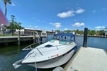 The Image of 2000 Crownline 242 CR boat docked by a scenic waterfront under a clear blue sky. - 0