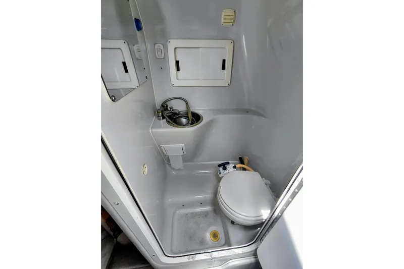 Slide: The Image of Compact bathroom in 2000 Crownline 242 CR boat, featuring toilet and sink. - 16